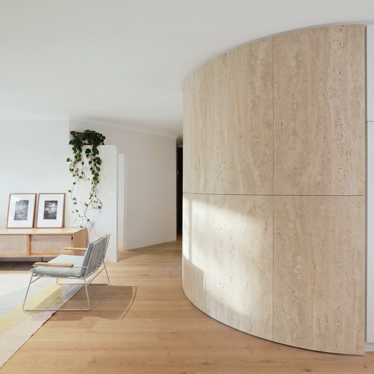 Parede curva revestida a travertino bege em sala luminosa